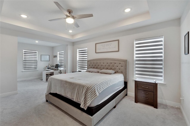 carpeted bedroom featuring a raised ceiling and ceiling fan