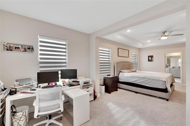 bedroom with ceiling fan, light carpet, a tray ceiling, and multiple windows