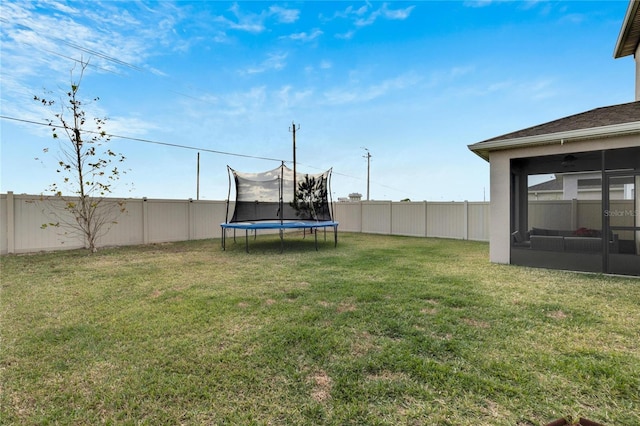 view of yard featuring a sunroom and a trampoline