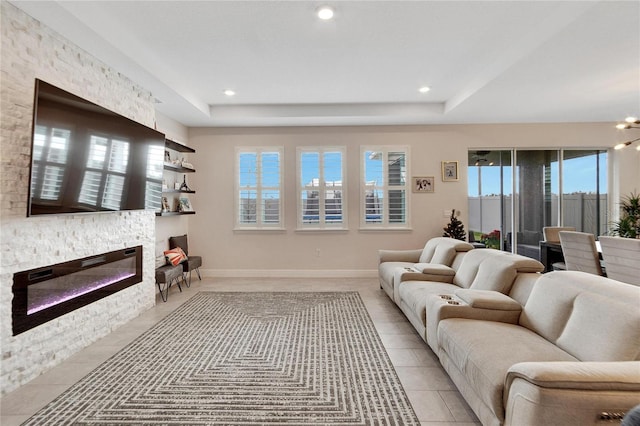 living room with a raised ceiling, a fireplace, and an inviting chandelier