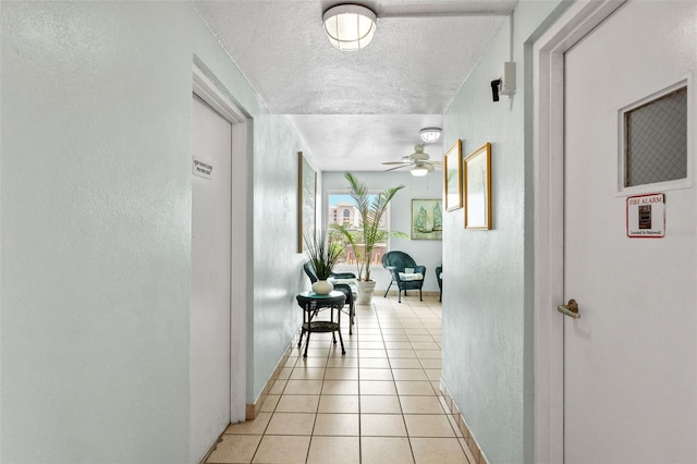 corridor with light tile patterned flooring and a textured ceiling