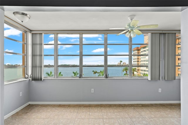 unfurnished room with a water view and ceiling fan