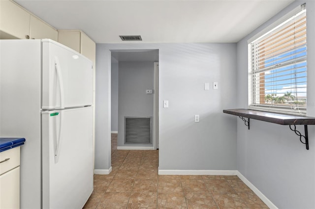 kitchen with white fridge and cream cabinetry