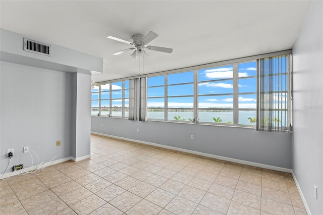 unfurnished room with a water view and ceiling fan