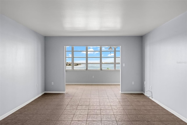 spare room with a water view and light tile patterned floors