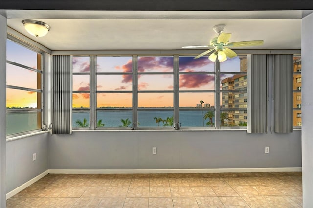 unfurnished room featuring ceiling fan and a water view