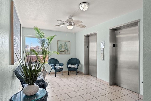 sitting room featuring light tile patterned floors, a textured ceiling, elevator, and ceiling fan