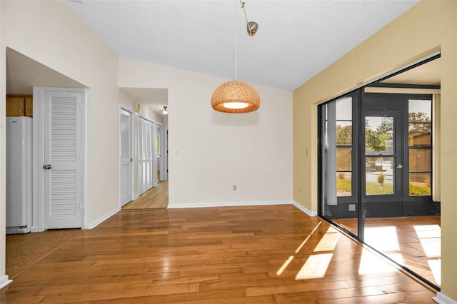 empty room featuring wood-type flooring, a textured ceiling, and lofted ceiling