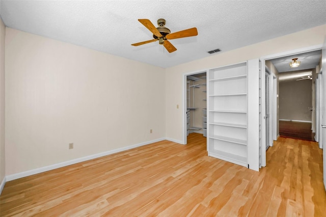 unfurnished bedroom with ceiling fan, a closet, light hardwood / wood-style floors, and a textured ceiling