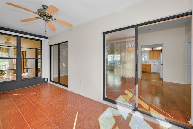 unfurnished sunroom featuring ceiling fan and plenty of natural light