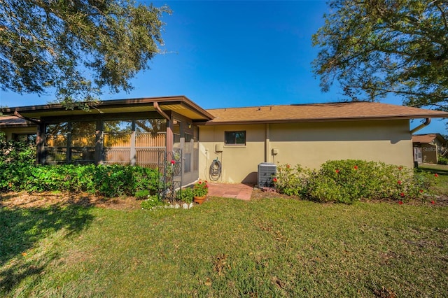 back of property with a lawn, a sunroom, and central AC unit