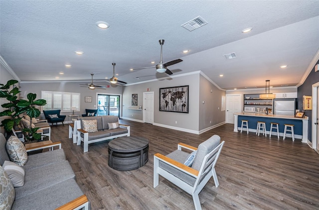 living room with a textured ceiling, vaulted ceiling, ceiling fan, crown molding, and wood-type flooring