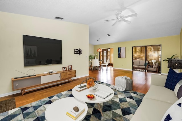 living room featuring a textured ceiling, ceiling fan, wood-type flooring, and vaulted ceiling