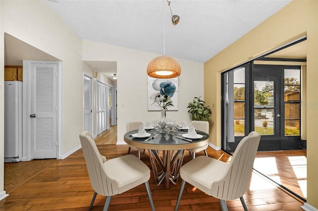 dining room with hardwood / wood-style floors and vaulted ceiling