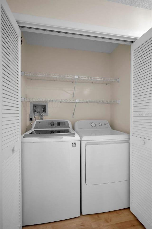 laundry area featuring washing machine and clothes dryer and light wood-type flooring