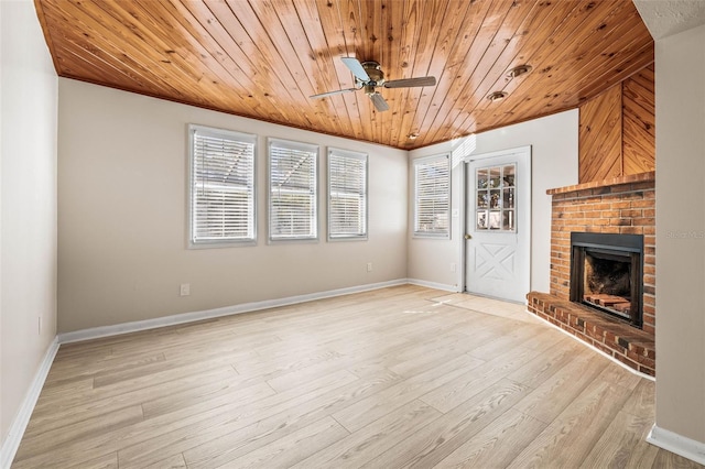 unfurnished living room with light wood-type flooring, ceiling fan, wooden ceiling, a fireplace, and wood walls