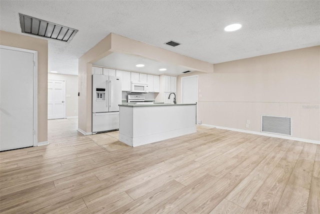 kitchen with white cabinetry, sink, a textured ceiling, white appliances, and light wood-type flooring