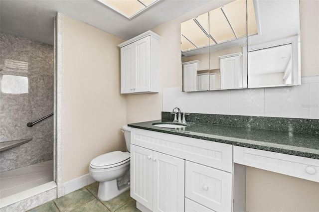 bathroom with tasteful backsplash, vanity, tiled shower, tile patterned flooring, and toilet