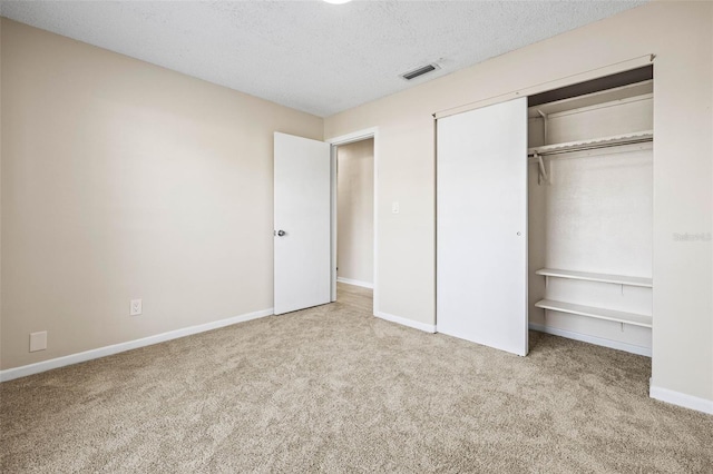 unfurnished bedroom with a closet, light colored carpet, and a textured ceiling