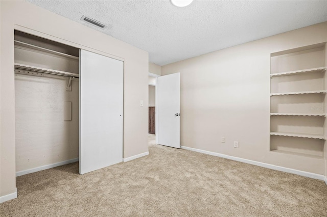 unfurnished bedroom with carpet, a textured ceiling, and a closet