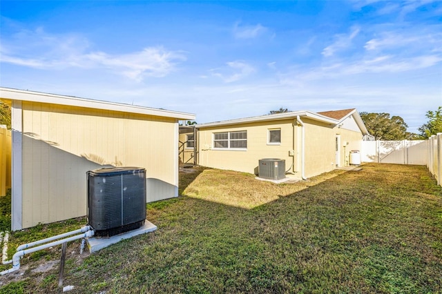 rear view of property with a yard and central AC unit