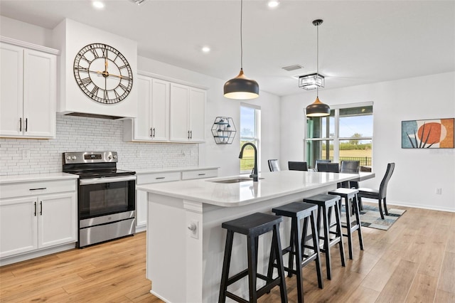 kitchen with sink, white cabinetry, a kitchen island with sink, and electric stove