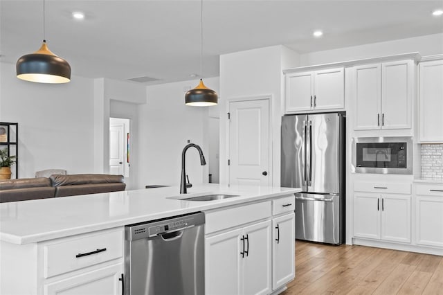 kitchen featuring decorative light fixtures, sink, white cabinetry, and stainless steel appliances