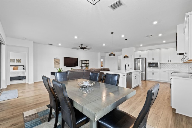 dining room featuring light wood-type flooring, ceiling fan, and sink