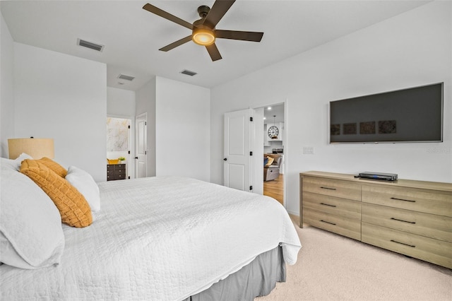 bedroom with ensuite bathroom, ceiling fan, and light colored carpet