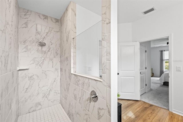 bathroom featuring hardwood / wood-style flooring, ceiling fan, and tiled shower