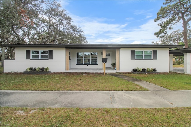 ranch-style house featuring covered porch and a front lawn