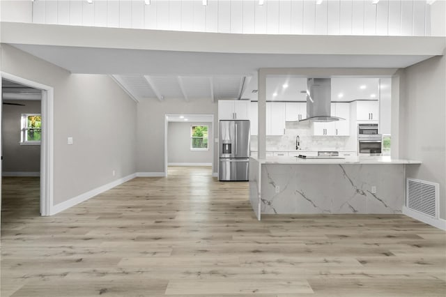 kitchen featuring light stone counters, ventilation hood, sink, stainless steel fridge with ice dispenser, and white cabinetry