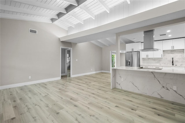 unfurnished living room with lofted ceiling with beams, light wood-type flooring, and sink