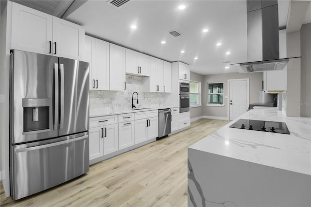 kitchen featuring light stone counters, light hardwood / wood-style flooring, extractor fan, white cabinets, and appliances with stainless steel finishes