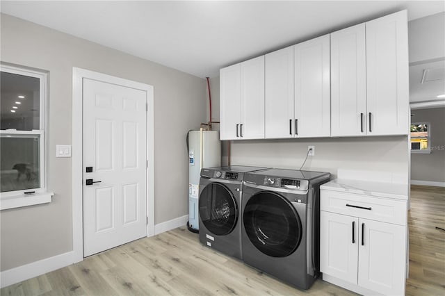 laundry room featuring electric water heater, cabinets, washer and dryer, and light wood-type flooring