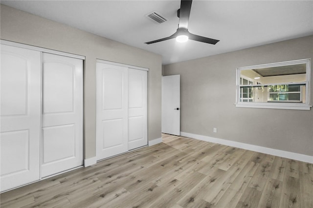 unfurnished bedroom featuring light hardwood / wood-style floors, ceiling fan, and multiple closets