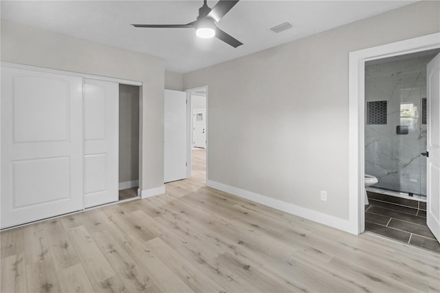 unfurnished bedroom featuring ensuite bathroom, a closet, ceiling fan, and light hardwood / wood-style flooring