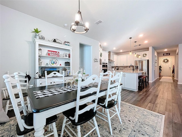 dining space with dark hardwood / wood-style flooring, a notable chandelier, and sink