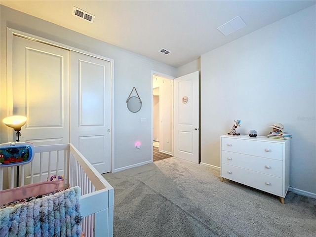 bedroom with a crib, light carpet, and a closet