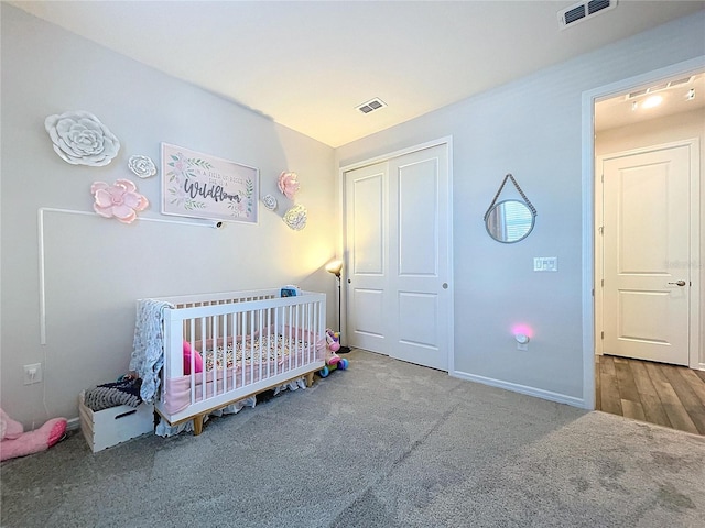 carpeted bedroom featuring a crib and a closet