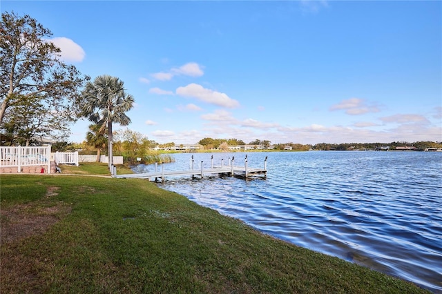 view of dock with a lawn and a water view