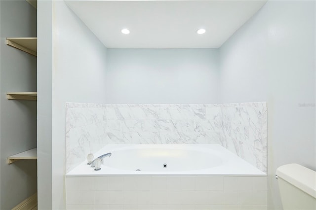 bathroom featuring tiled tub and toilet