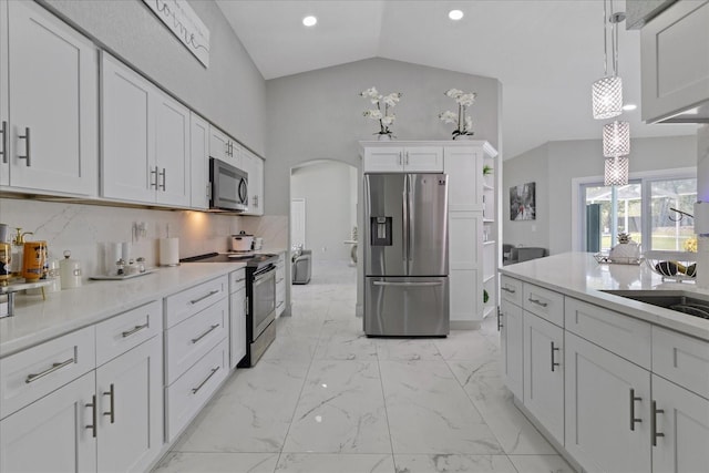 kitchen featuring decorative backsplash, stainless steel appliances, vaulted ceiling, decorative light fixtures, and white cabinets