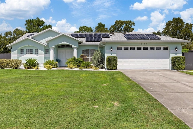 view of front of property with solar panels, a garage, and a front yard