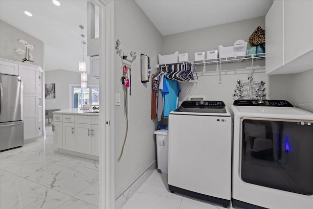 clothes washing area with washing machine and dryer and cabinets