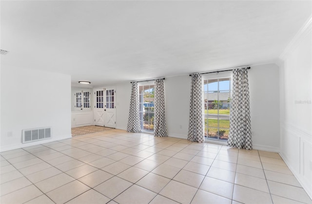 spare room featuring crown molding, plenty of natural light, and light tile patterned floors