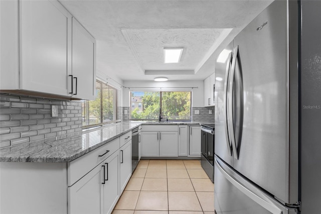 kitchen featuring light stone countertops, white cabinets, stainless steel appliances, and light tile patterned floors