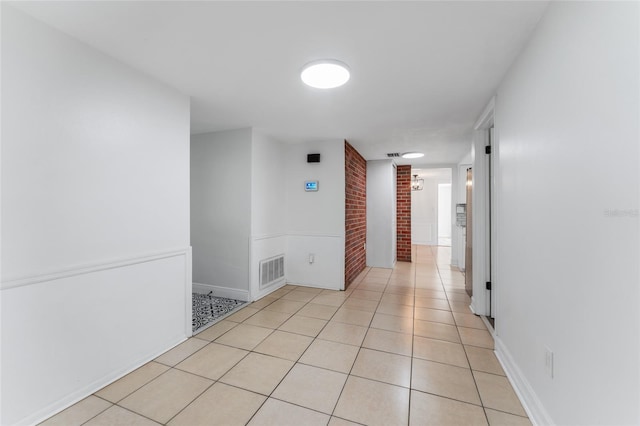 hallway with light tile patterned flooring and brick wall