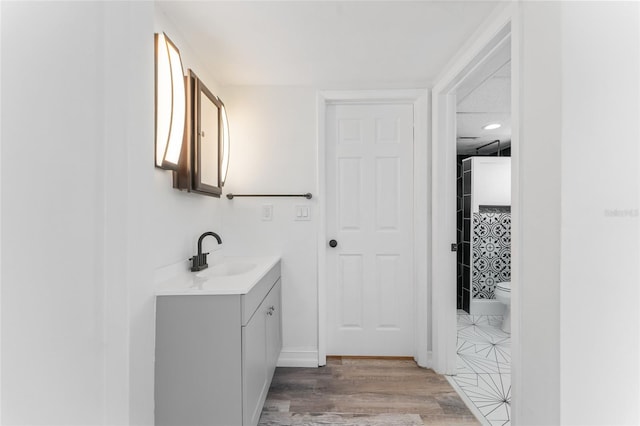 bathroom with hardwood / wood-style floors, vanity, and toilet