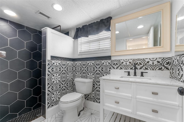 bathroom featuring a shower, vanity, tile walls, and toilet